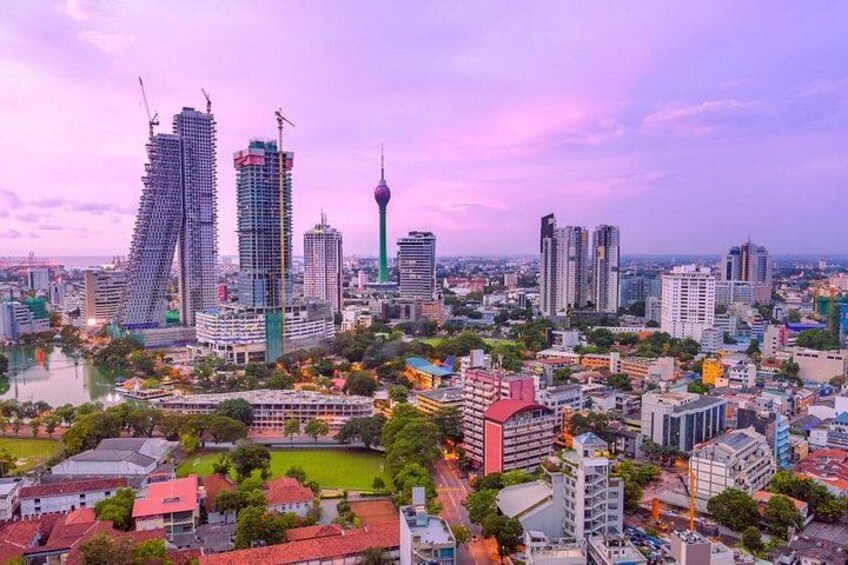 A cityscape with modern buildings, a prominent tower, and a mix of residential and commercial structures. 2