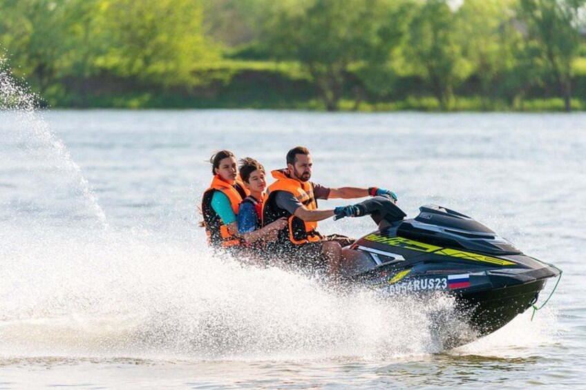 A jet ski with three people wearing life jackets on a body of water. 4