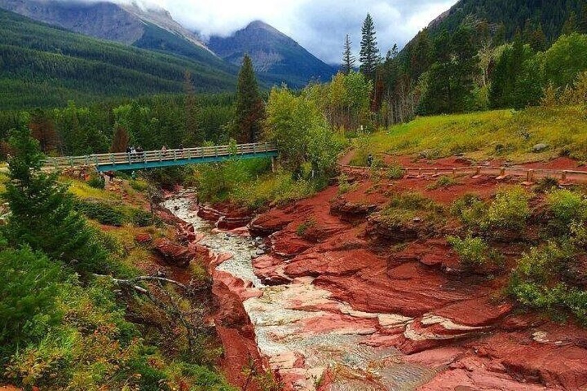 A river flowing through a red rock canyon with a bridge and forested mountains in the background. 2