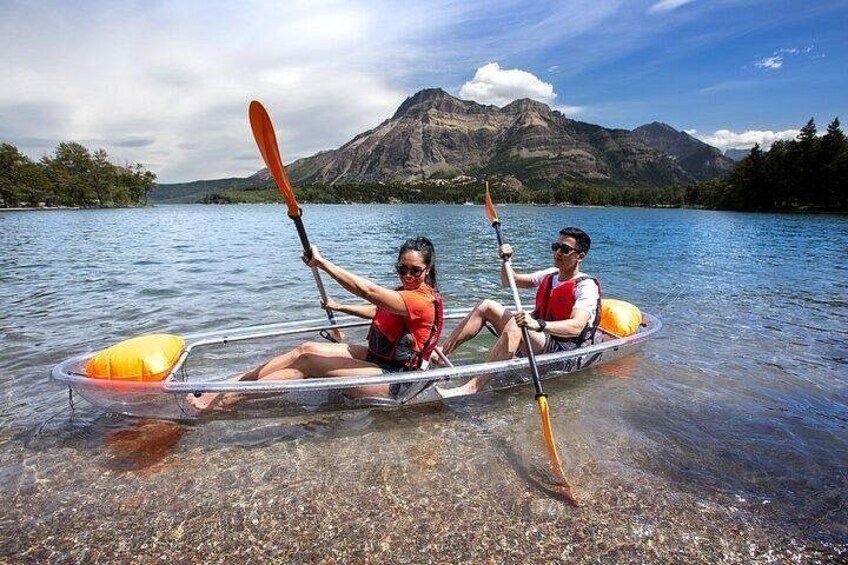 Two people kayaking on a calm lake with mountains in the background. 2