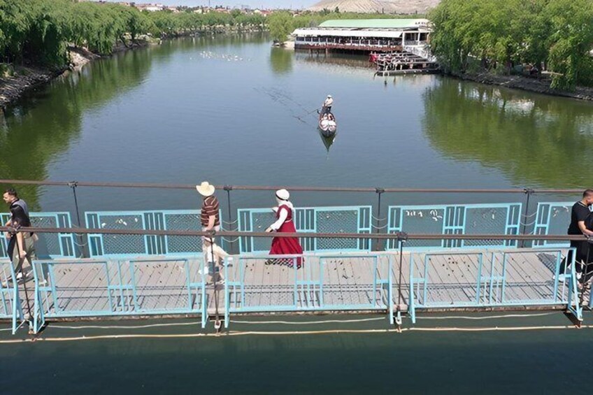 A river with a boat, a bridge, and people on the bridge. 4