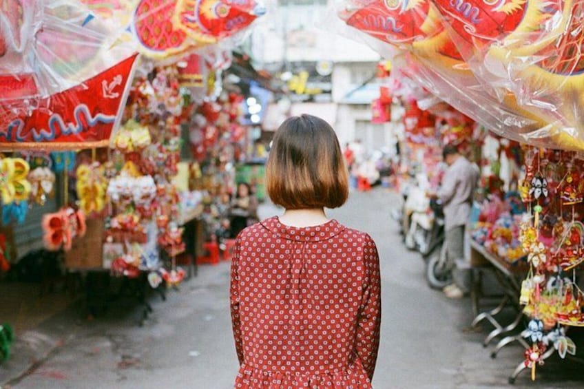 Une personne se promène dans un marché où l’on peut voir des parasols et des étals aux couleurs vives. 1