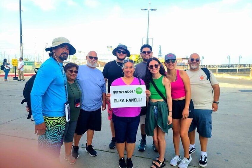 A group of people posing for a photo with a sign that reads 'BIENVENIDOS ELISA FANELLI'. 2