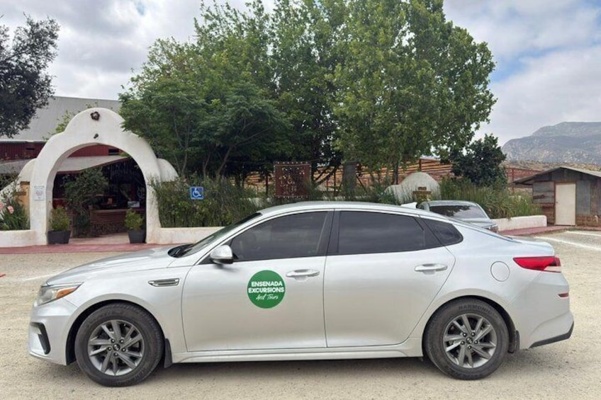 A white car parked in front of a building with a green logo on the side. 5
