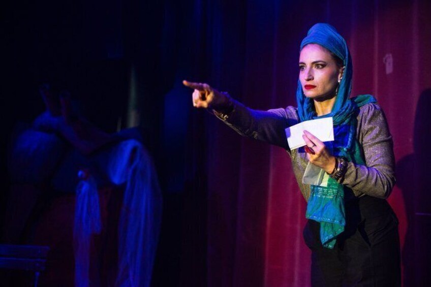 A person on stage with a microphone, holding a piece of paper. 2