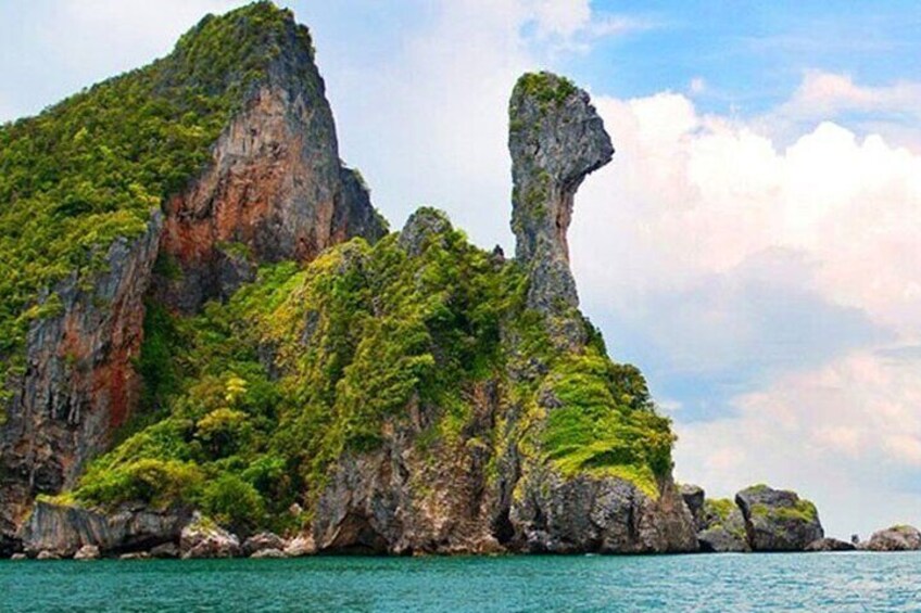 A coastal landscape with a prominent rock formation and lush green vegetation. 1