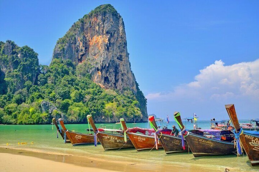 A row of traditional boats on a beach with a large limestone cliff in the background. 5