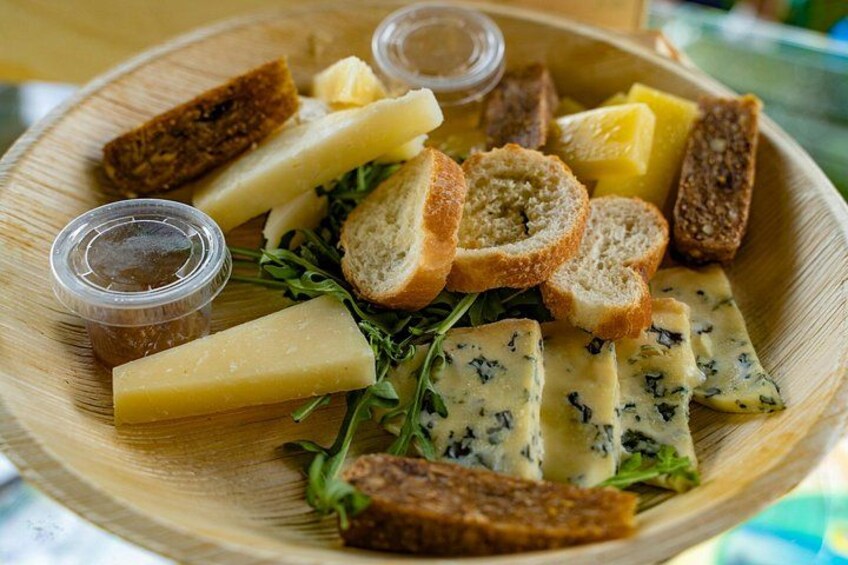 Ein Holzbrett mit verschiedenen Käsesorten, Brot und Salat. 2