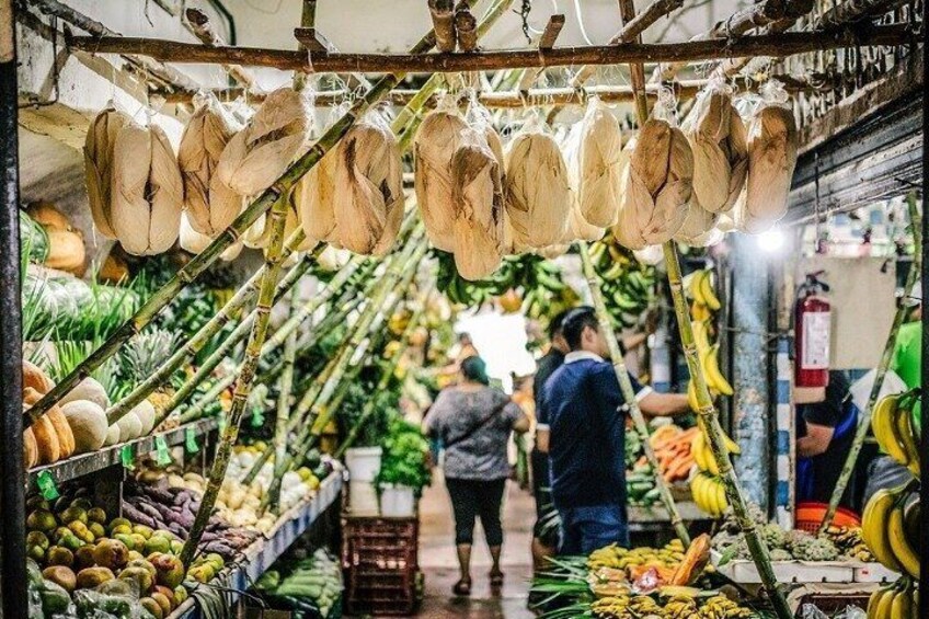 A market with hanging coconuts and various fruits on display. 4