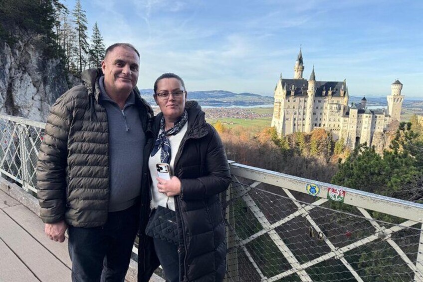 Two people standing on a bridge with a castle in the background. 2