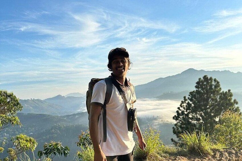 A person hiking with a backpack, surrounded by a mountainous landscape and greenery. 2