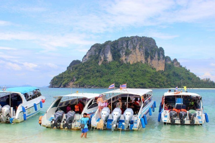 Three boats docked at a pier with a mountainous island in the background. 1