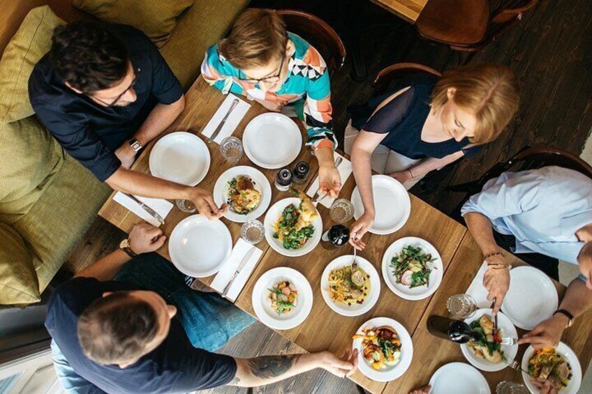 A group of people dining around a wooden table with various dishes. 3