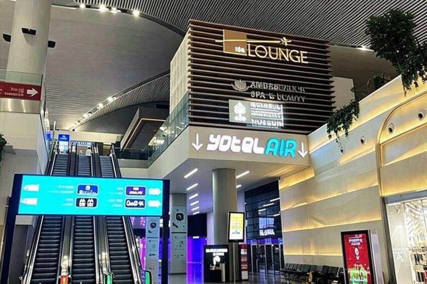 An indoor shopping mall with an escalator, a lounge area, and a Total Air sign. 4