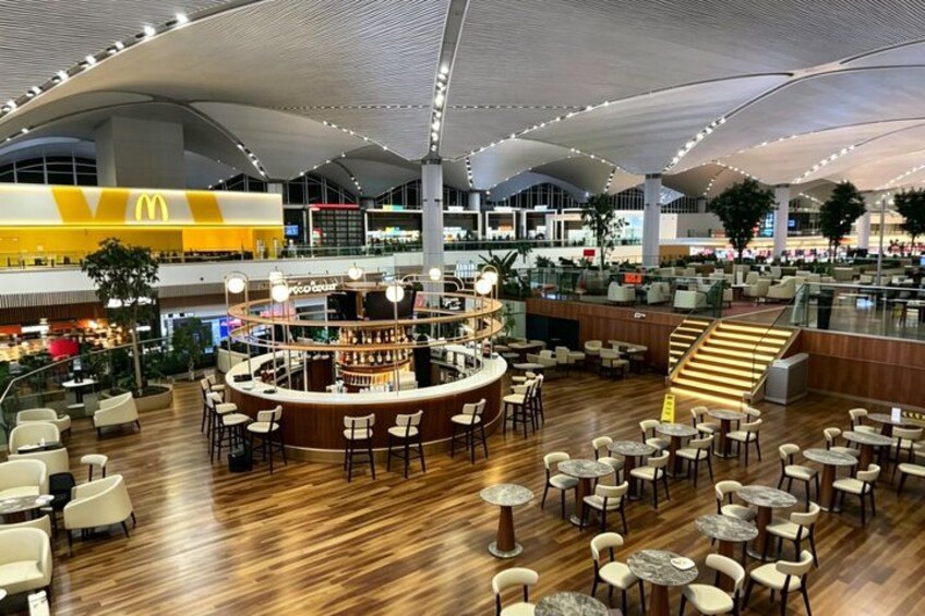 A spacious indoor area with a central bar, multiple seating areas, and a high ceiling with a unique architectural design. 1