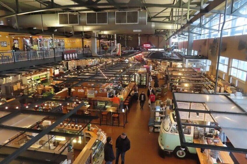 A large indoor market with multiple levels, various stalls, and people shopping. 3