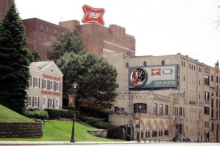 A historic building with a Miller sign, a Frederick Miller Plank Road Brewery sign, and a Four Blocks Tour sign. 4