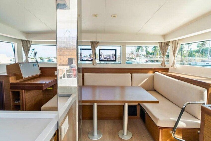 A boat interior with a dining area, a TV, and a view of the marina. 2
