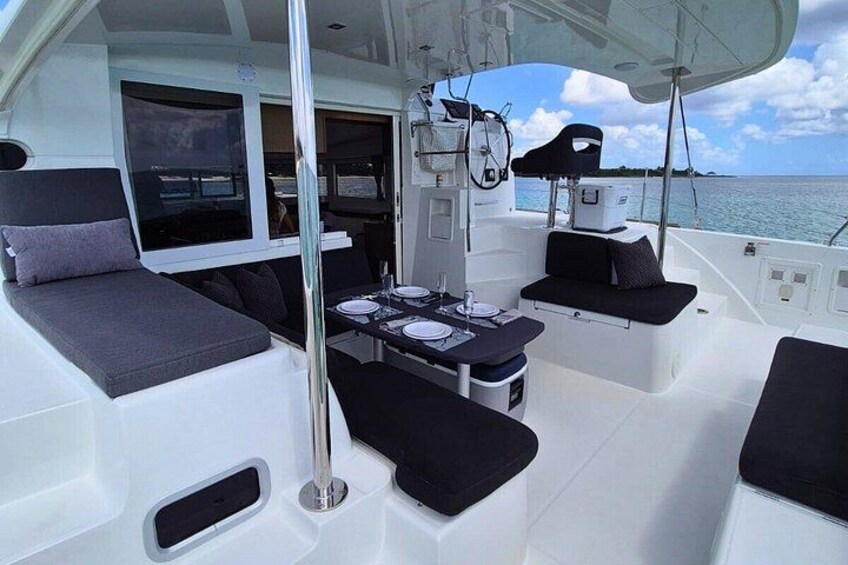 A boat's deck with seating, a table, and a steering wheel. 5