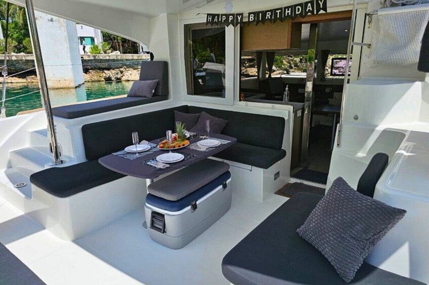 A boat's interior with a dining area, a birthday banner, and a view of the water. 4