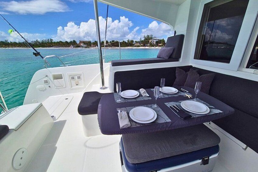 A boat's dining area with a table set for two, surrounded by cushioned seating. 4