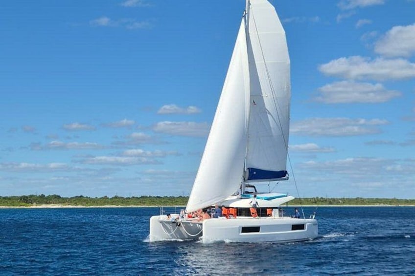 A white sailboat with a blue canopy sailing on calm blue waters. 1