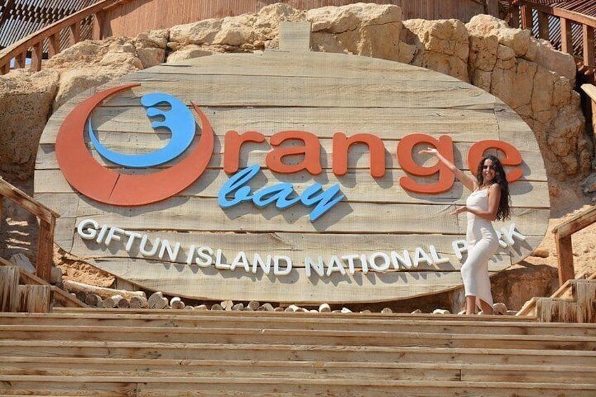 Een houten bord met de tekst 'Orange Bay' en 'Nationaal Park Giftun Eiland' in een strandomgeving. 3