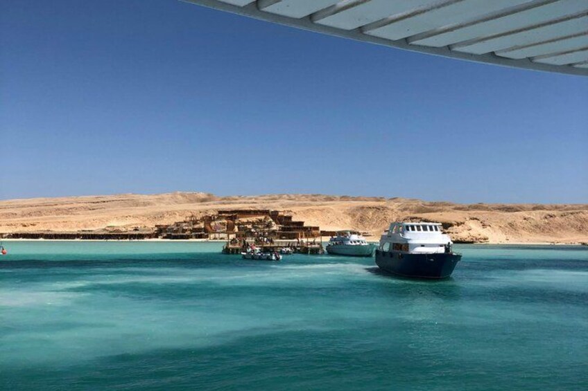 Un cuerpo de agua con barcos, una playa arenosa y un edificio distante. 2