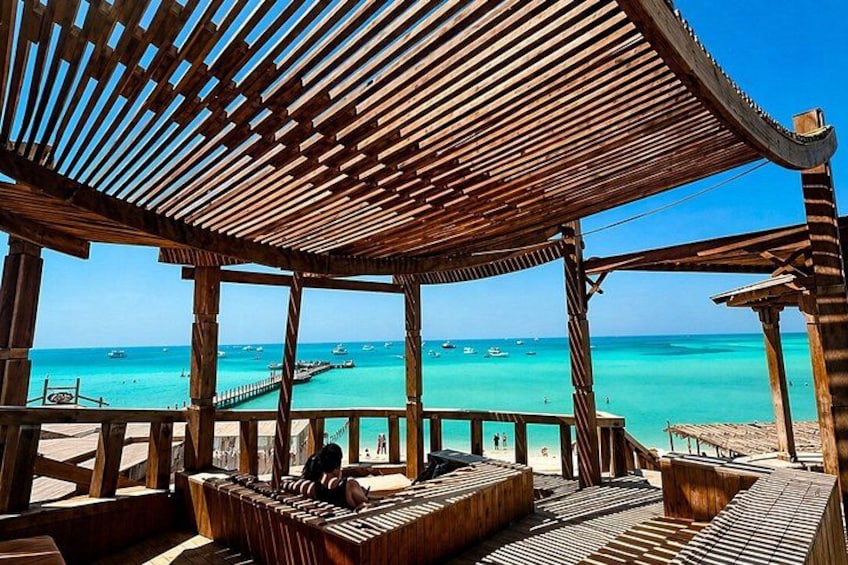 A wooden gazebo overlooking turquoise waters with boats. 5