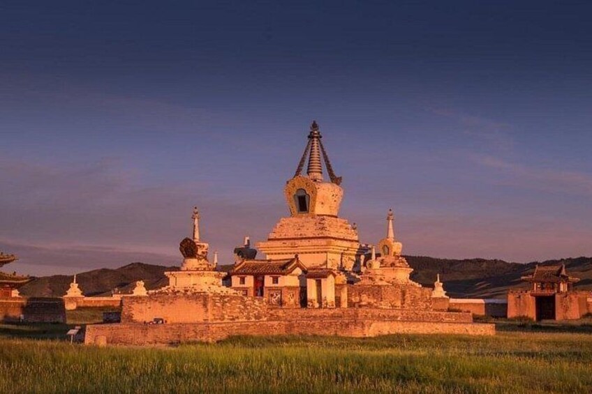 A large stupa with multiple tiers, surrounded by smaller structures, set against a hilly backdrop. 1