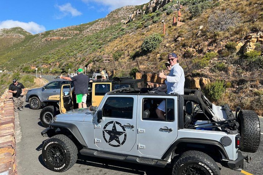 A Jeep with a star emblem parked on a road with a mountainous backdrop. 2
