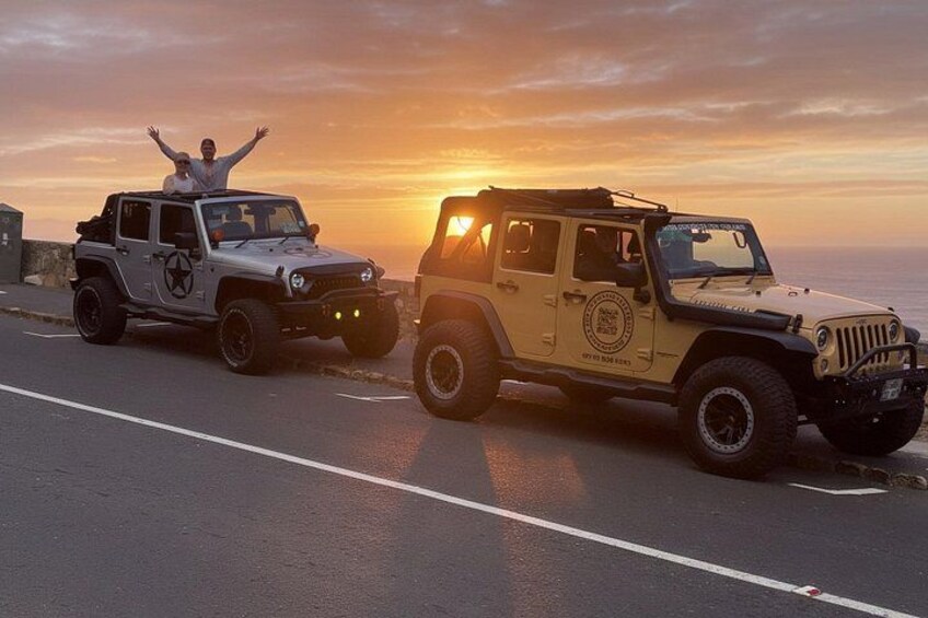 Two off-road vehicles on a road with a sunset in the background. 1