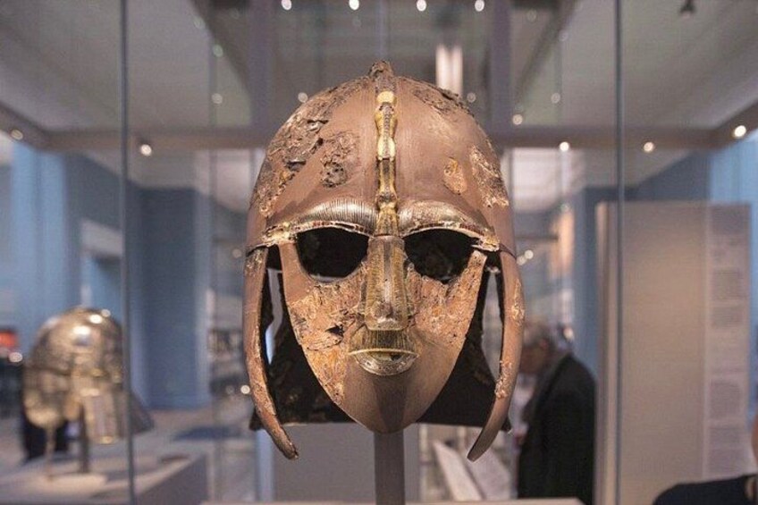 A bronze helmet with intricate designs, displayed in a museum setting. 3