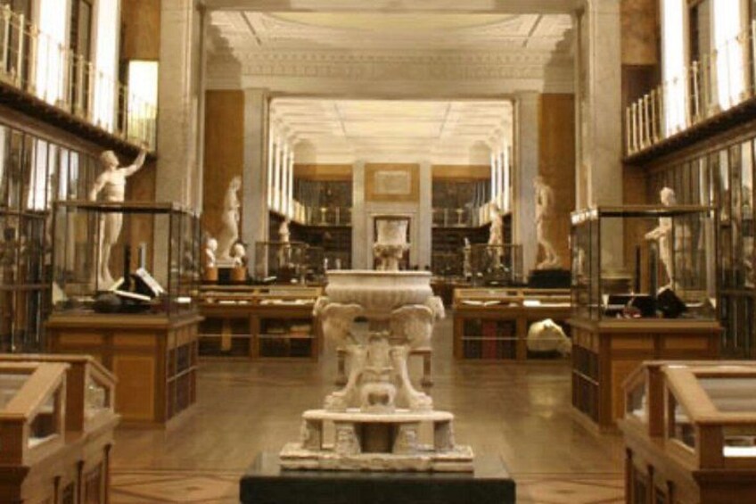 A grand library with marble floors, classical statues, and bookshelves filled with books. 4