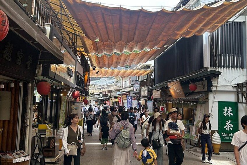 Eine belebte Marktstraße mit Fußgängern, traditioneller Bebauung und einer überdachten Passage. 1