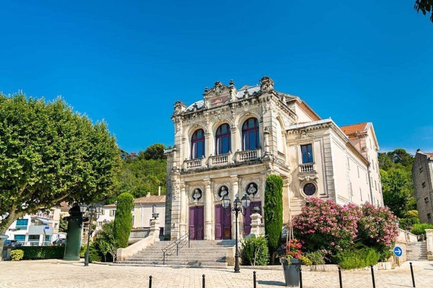 A historic building with ornate architecture, a staircase leading to the entrance, and a clear blue sky. 1