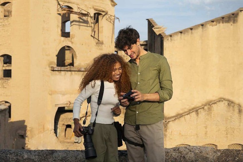 Two people standing in front of an old building with visible damage and graffiti. 5