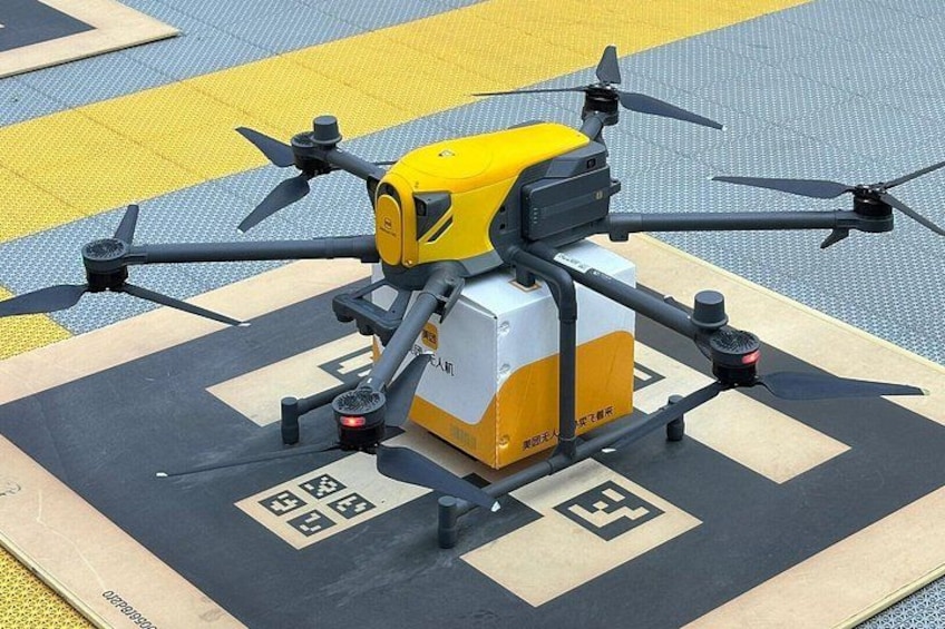 A drone on a landing pad with a yellow and white box underneath. 3