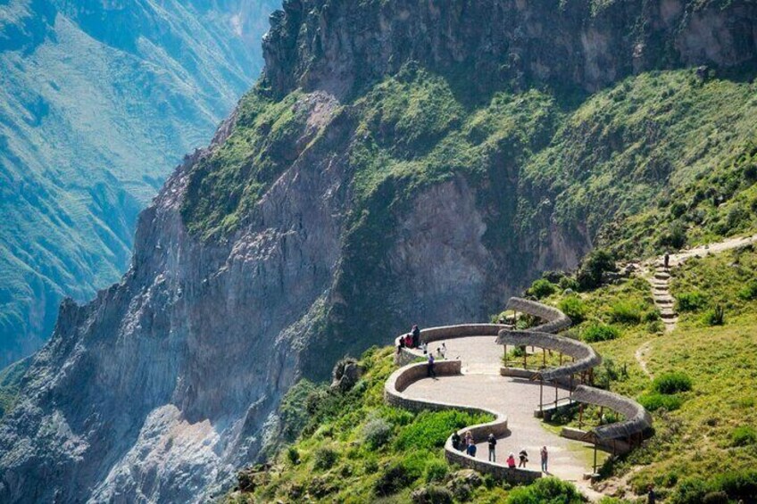 A winding stone pathway along a mountain ridge with lush greenery and steep cliffs. 5
