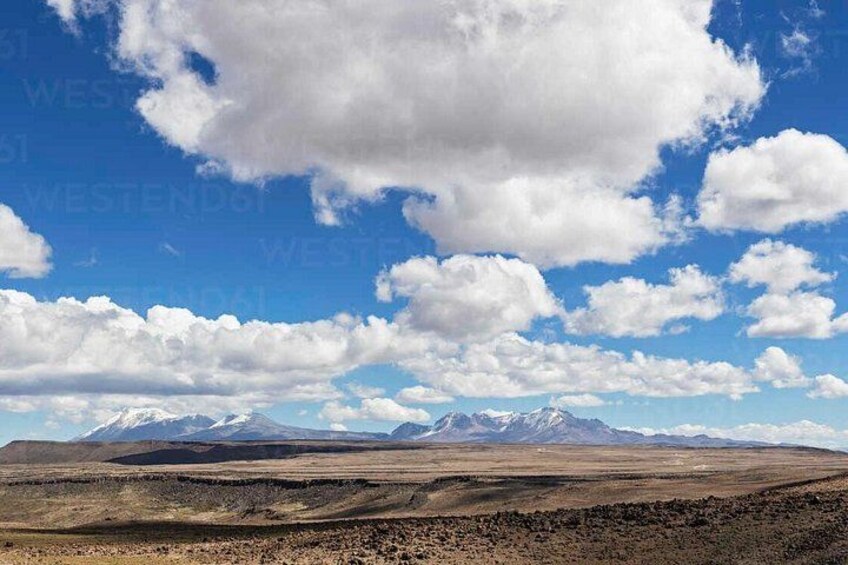 A mountainous landscape with a clear sky and scattered clouds. 5