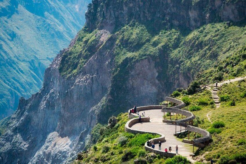 A winding stone pathway along a mountainous landscape with lush greenery and steep cliffs. 4