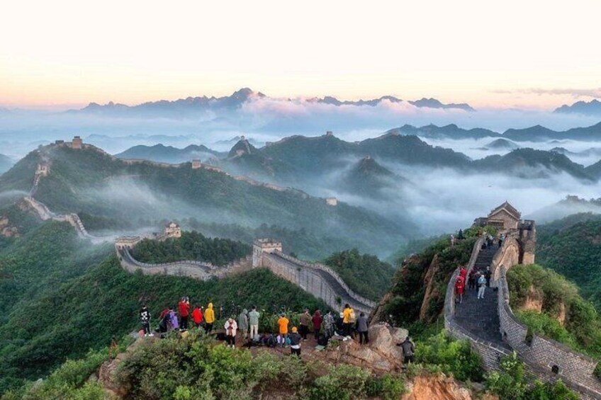 The Great Wall of China winding through misty mountains, with tourists on the path. 5