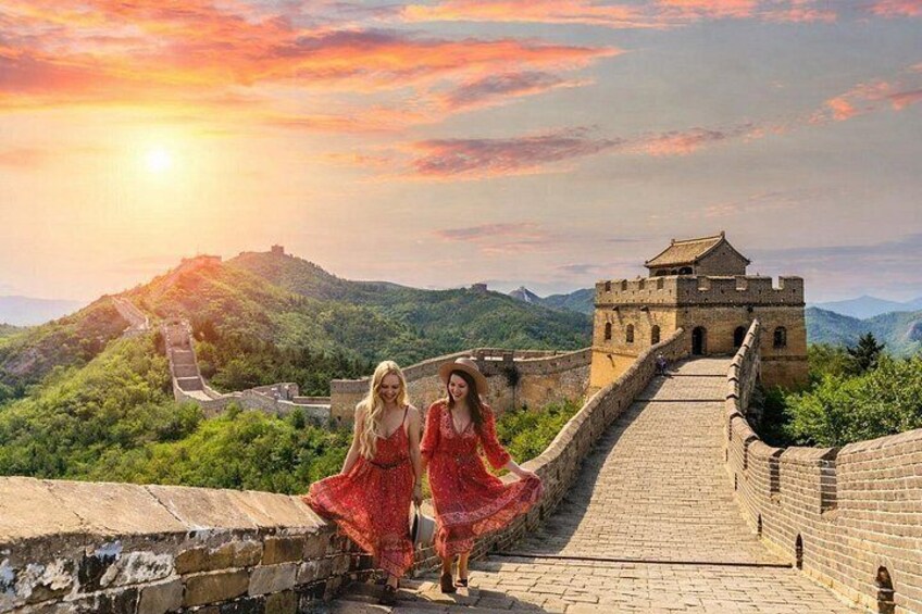 A long stone wall with a watchtower, lush green hills, and a sunset. 1