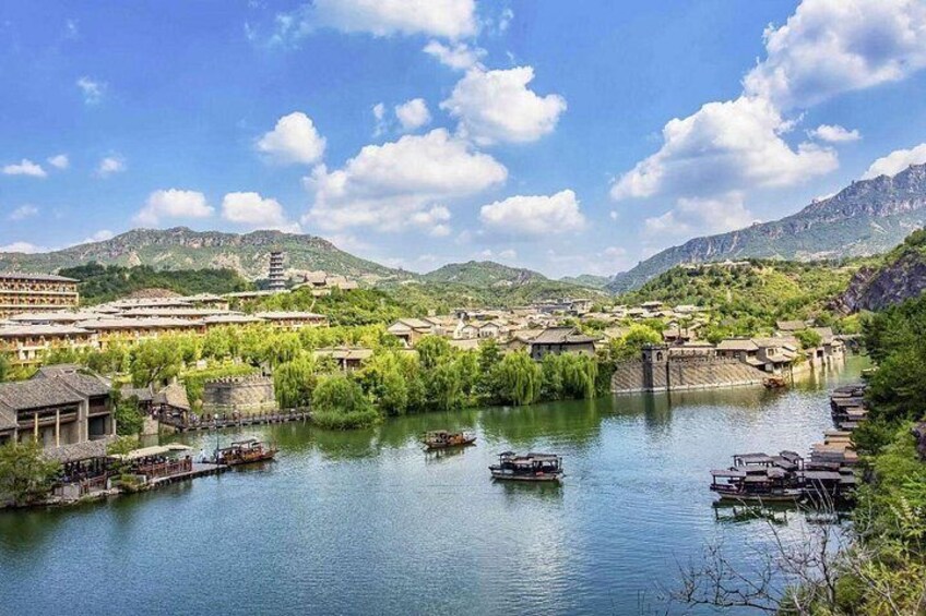 A river with boats, traditional buildings, and mountains in the background. 3