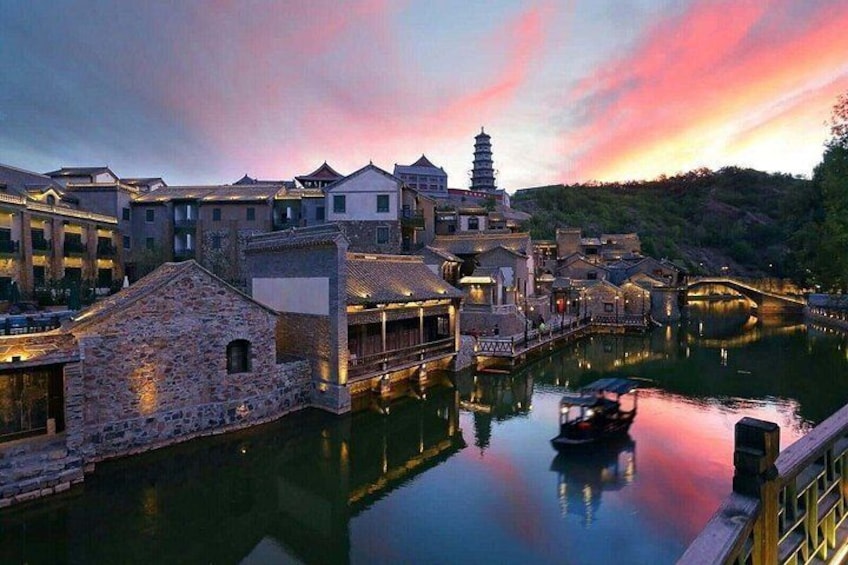 A traditional village with stone buildings, a river, and a pagoda. 4