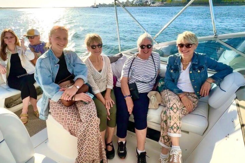 A group of people on a boat with water and a distant shoreline in the background. 1