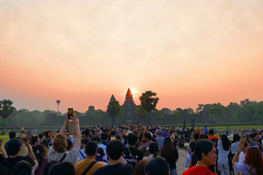 A crowd of people at a historical site during sunset. 1