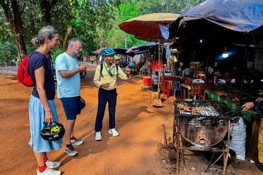 A group of people at a roadside food stall with a grill. 2