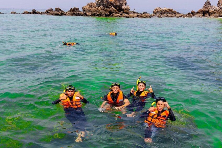 A group of people snorkeling in clear water with rocky formations in the background. 5