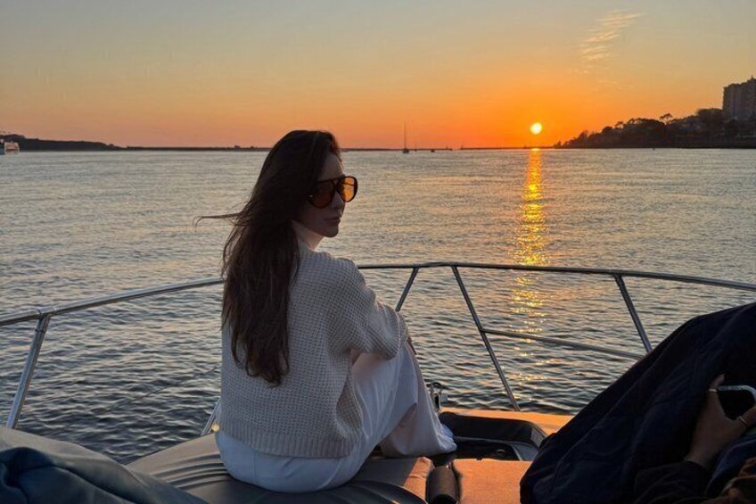 A person sitting on a boat during sunset, with the sun reflecting on the water. 2